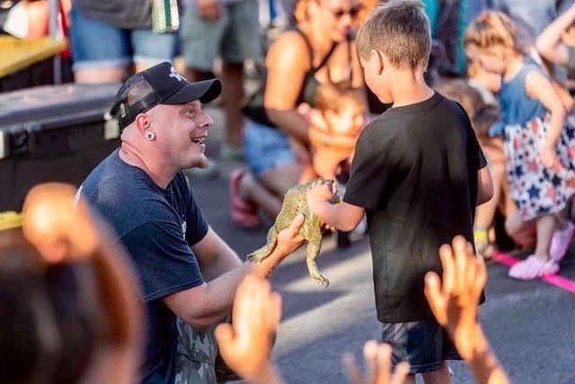 A group of kids at a birthday party reaching to touch a bearded dragon