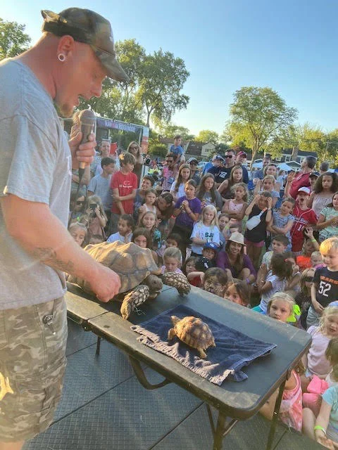 A library event with children sitting attentively during the reptile show